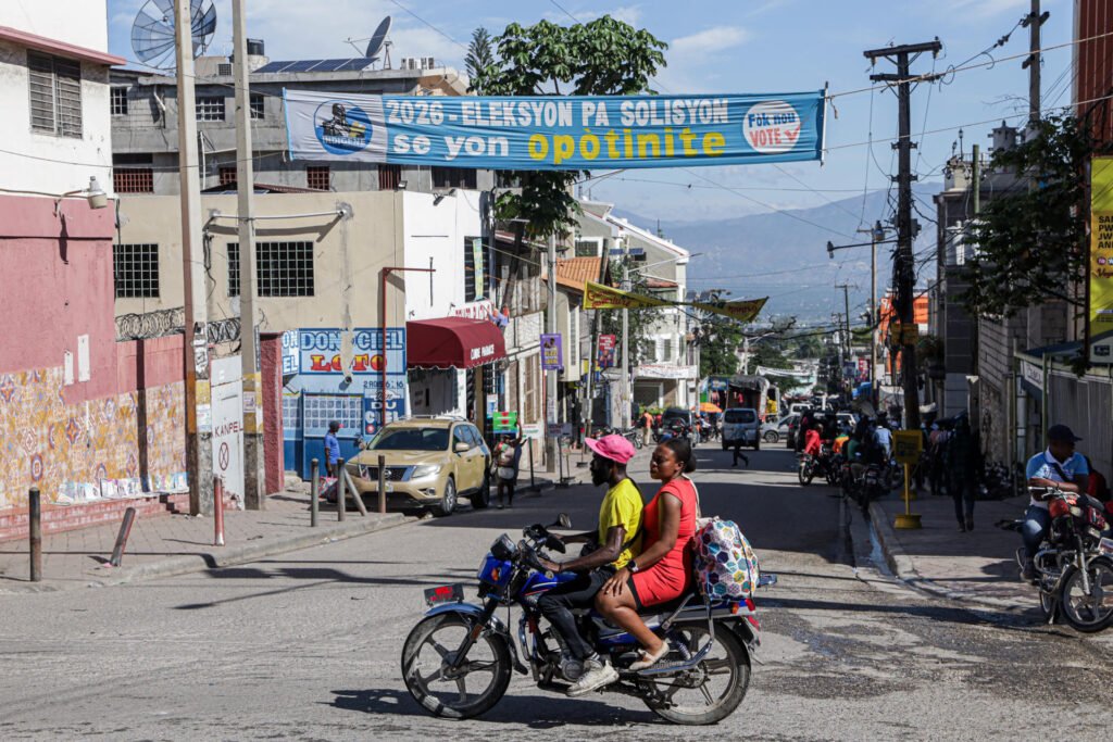 Calle de Puerto Príncipe con una pancarta electoral y una moto en primer plano