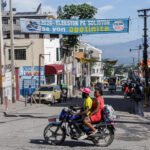 Calle de Puerto Príncipe con una pancarta electoral y una moto en primer plano