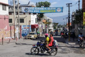 Calle de Puerto Príncipe con una pancarta electoral y una moto en primer plano