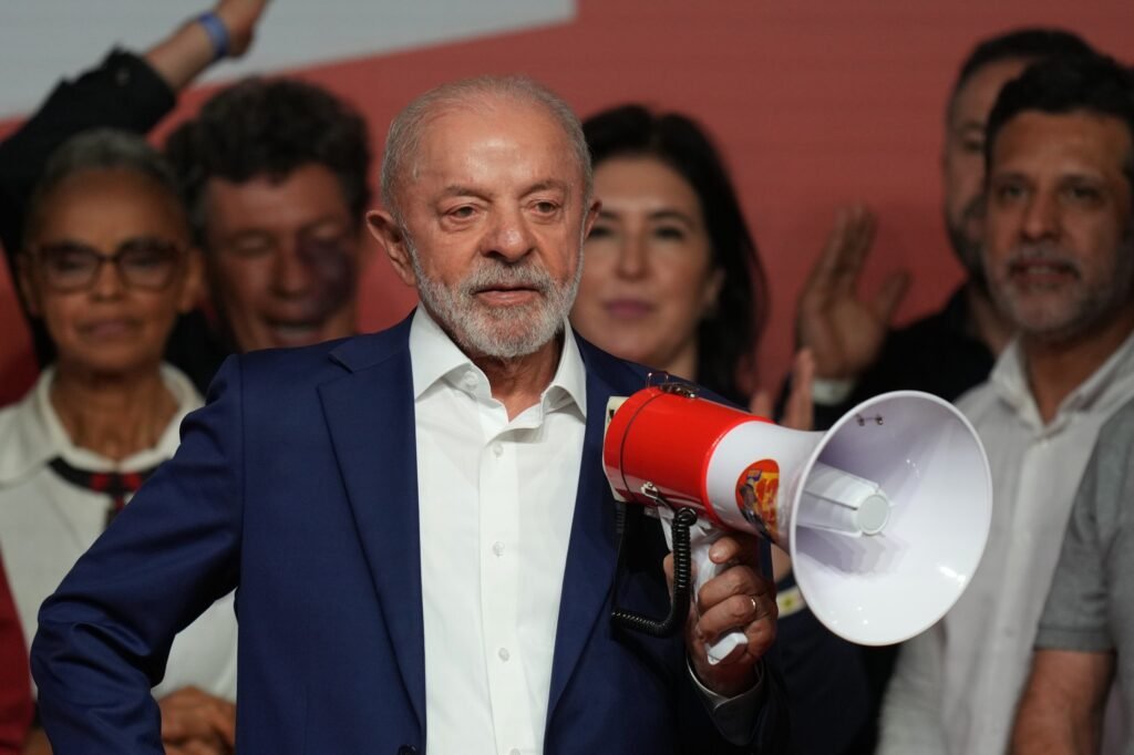 El presidente de Brasil, Luiz Inácio Lula da Silva, sostiene un megáfono con la estrella del Partido de los Trabajadores durante un acto de campaña, acompañado por dirigentes de su partido. Imagen de archivo de la campaña de esta elección, publicada por Listín Diario al confirmarse el balotaje contra Flávio Bolsonaro.