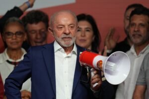 El presidente de Brasil, Luiz Inácio Lula da Silva, sostiene un megáfono con la estrella del Partido de los Trabajadores durante un acto de campaña, acompañado por dirigentes de su partido. Imagen de archivo de la campaña de esta elección, publicada por Listín Diario al confirmarse el balotaje contra Flávio Bolsonaro.
